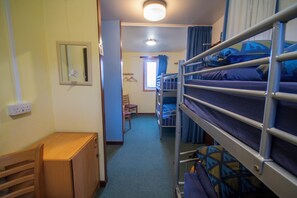 A bunk room with a bunk bed, a wooden cabinet, a chair, and a window with curtains. - Achmelvich Beach Youth Hostel (Achmelvich)