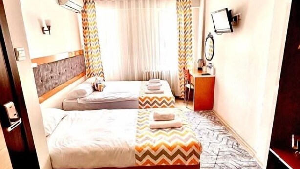 Habitación de hotel con dos camas, un escritorio, una silla, un espejo y una alfombra estampada.