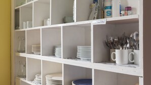 A kitchen with white shelves, glassware, plates, and utensils. - Durness Youth Hostel (Durness)