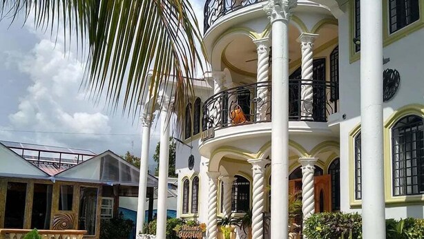 Un edificio a più piani con un'imponente facciata, colonne e un balcone con ringhiera.