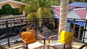 Un balcone con posti a sedere all'aperto, una colonna bianca e vista su un edificio con tetto rosso.