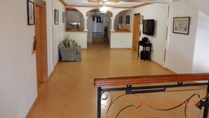 Un'ampia sala con ventilatore a soffitto, una scala e un'area pranzo con televisore.