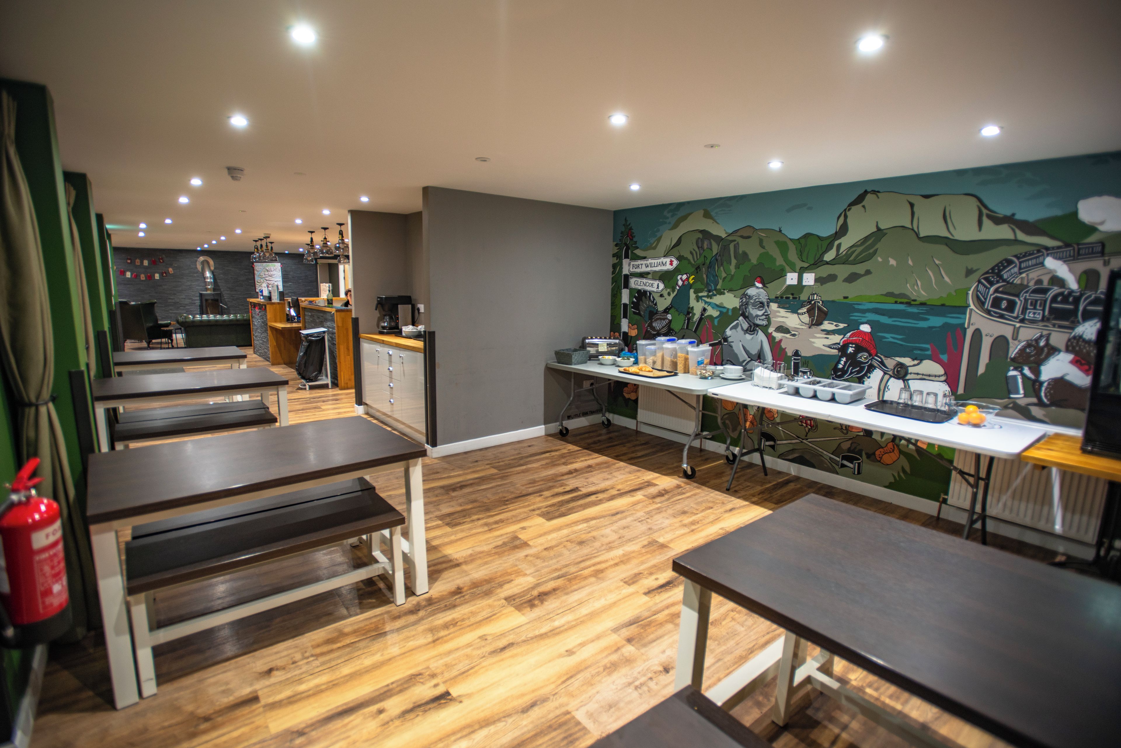 Een restaurantinterieur met houten vloeren, tafels en een muurschildering.