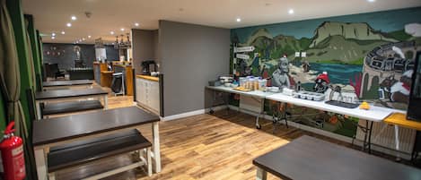 A restaurant interior with wooden flooring, tables, and a mural on the wall.