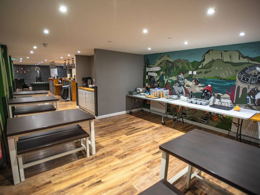 A restaurant interior with wooden flooring, tables, and a mural on the wall.