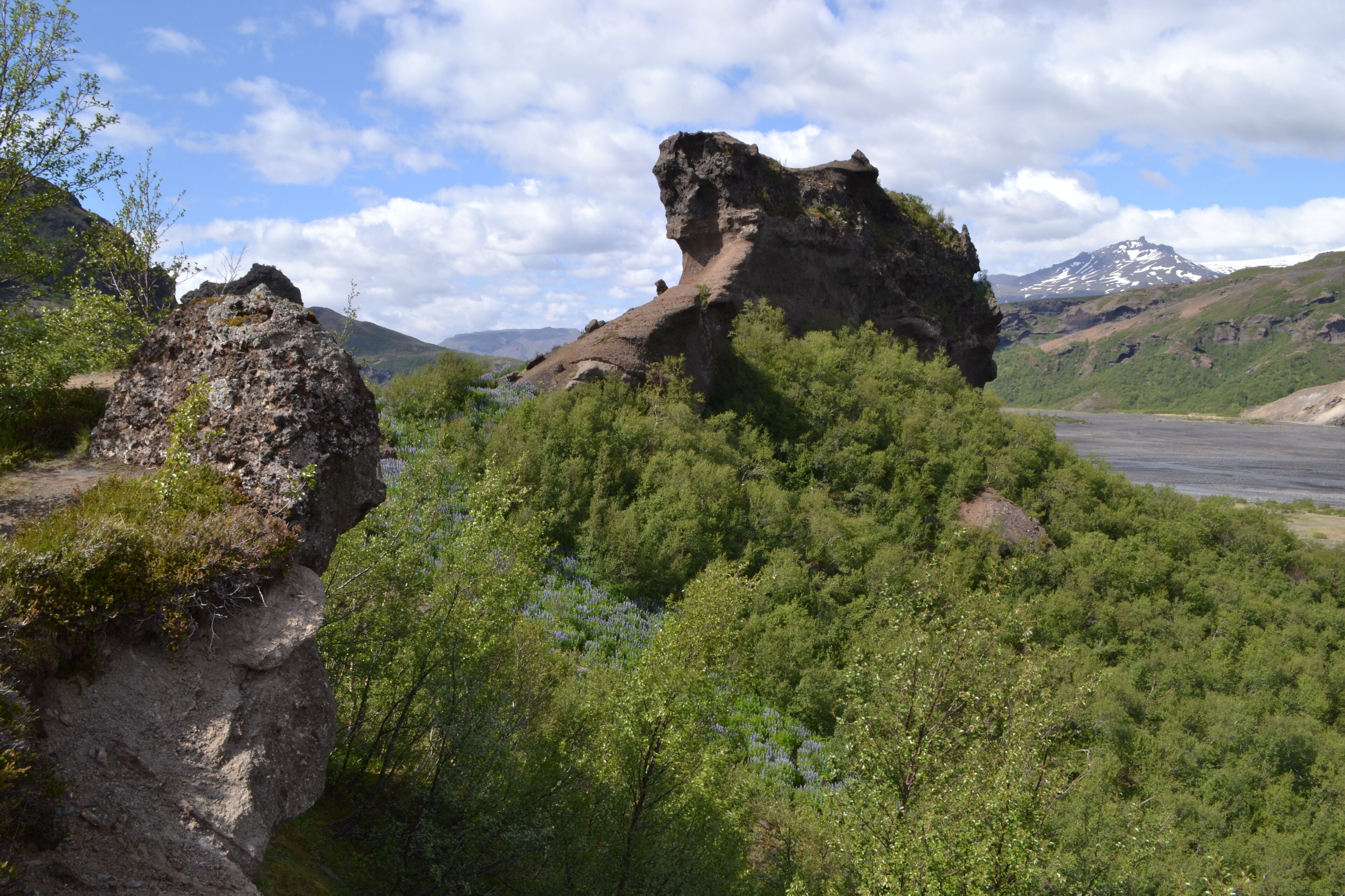 Un paisaje montañoso con una formación rocosa destacada y vegetación verde densa.