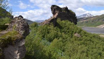 Un paisaje montañoso con una formación rocosa destacada y vegetación verde densa.