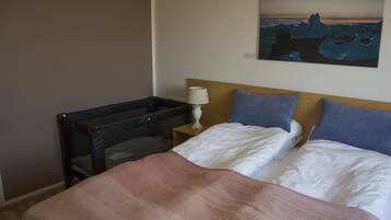 A bedroom with a bed, pillows, a nightstand, a lamp, and a painting of a glacier on the wall.