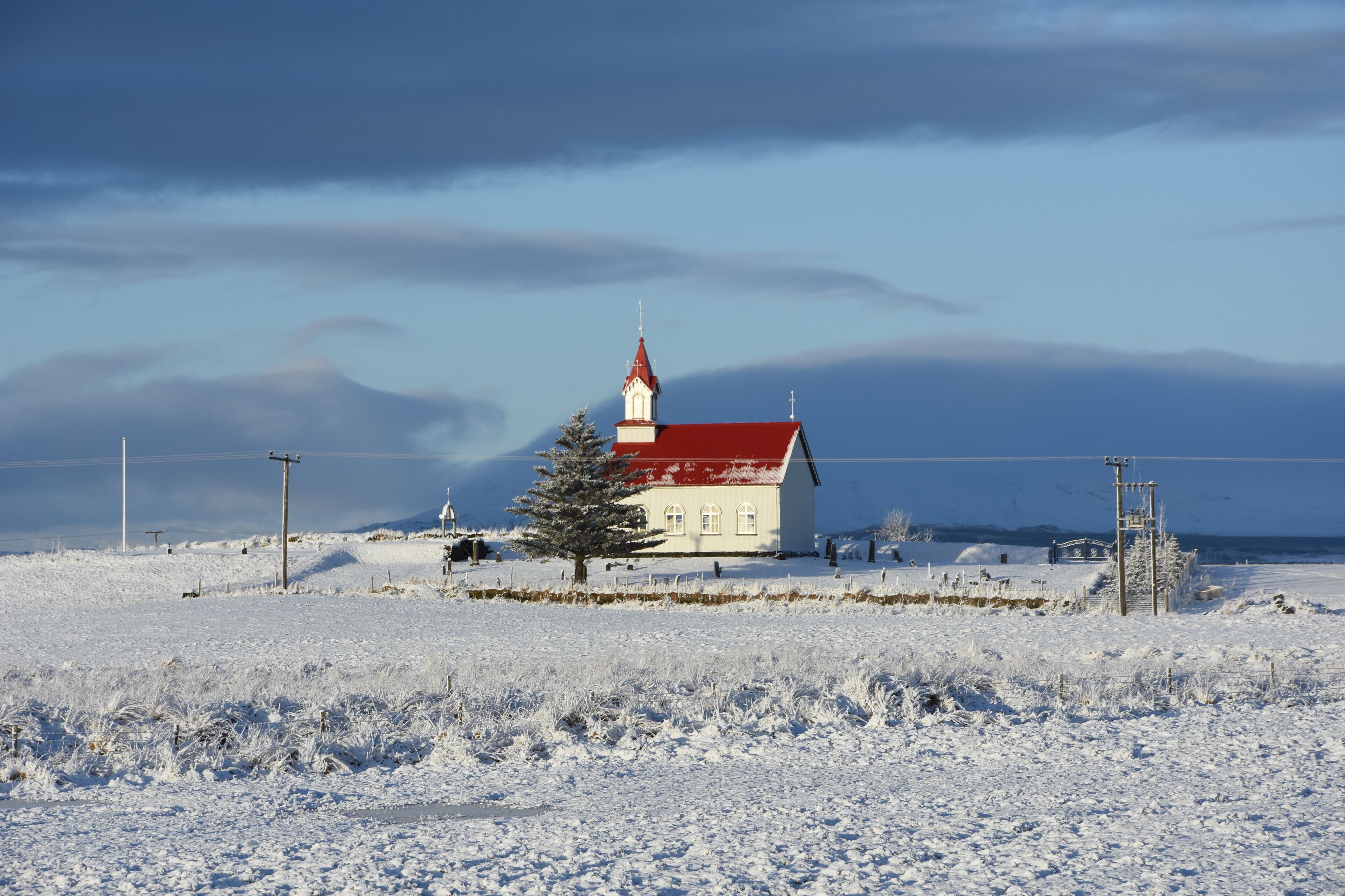 A snow-covered landscape with a white building featuring a red roof and a tall white tower.