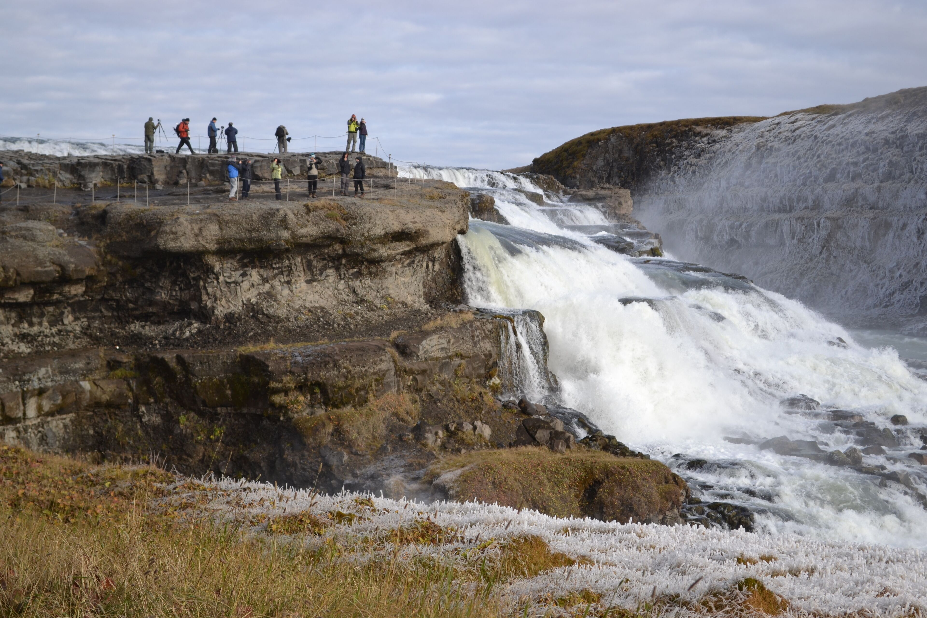 A waterfall cascading over rocky terrain with people observing from a viewing platform.