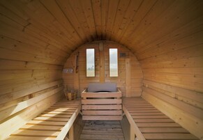 Una cabaña de madera con una cama en el altiloce y un ventanal pequeño.