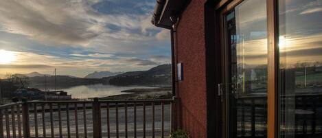 A wooden deck with a view of a lake and mountains.