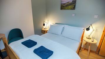 Una habitación de hotel con una cama, dos lámparas de noche, una silla y un cuadro en la pared.
