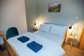 A hotel room with a bed, two bedside lamps, a chair, and a painting on the wall. - Portree Youth Hostel (Portree)