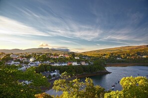 A coastal town with buildings along the shoreline, a body of water, and hills in the background.