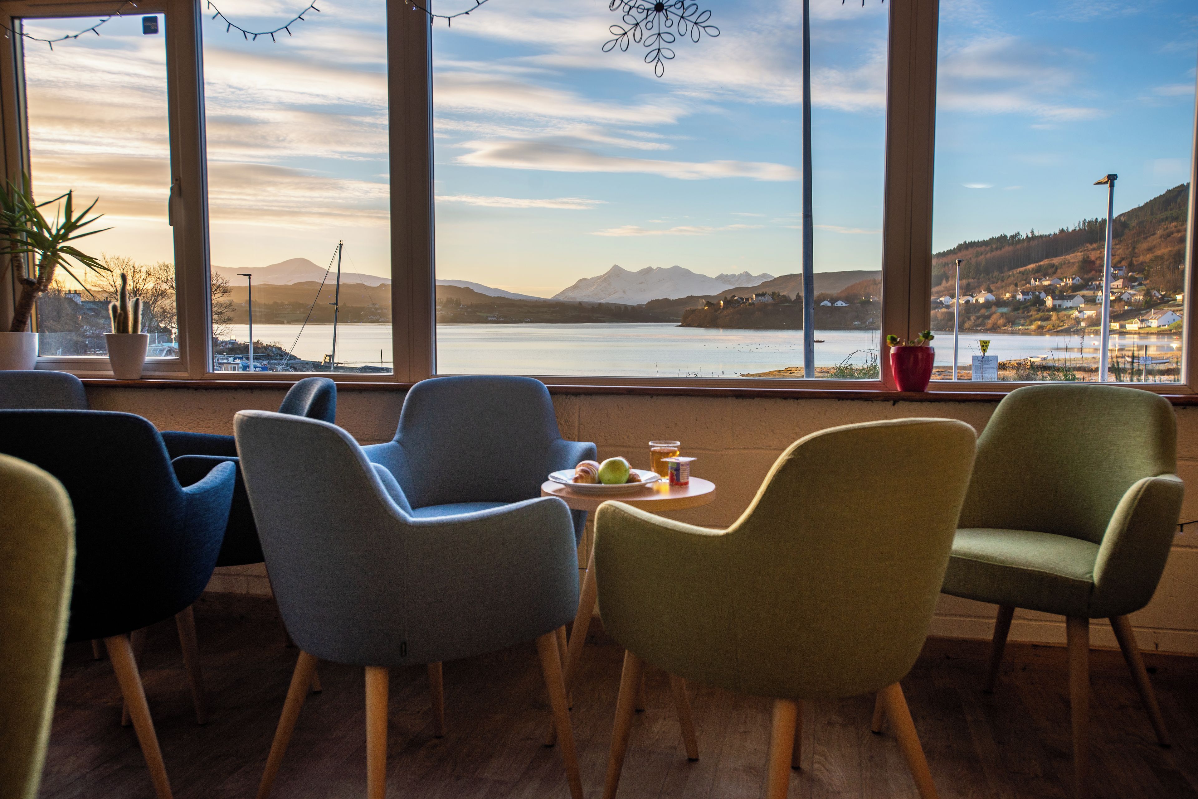 A seating area with chairs facing a large window overlooking a lake and mountains.