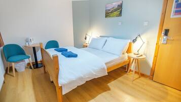 A bedroom with a bed, two bedside tables, a chair, and a small table with a lamp.