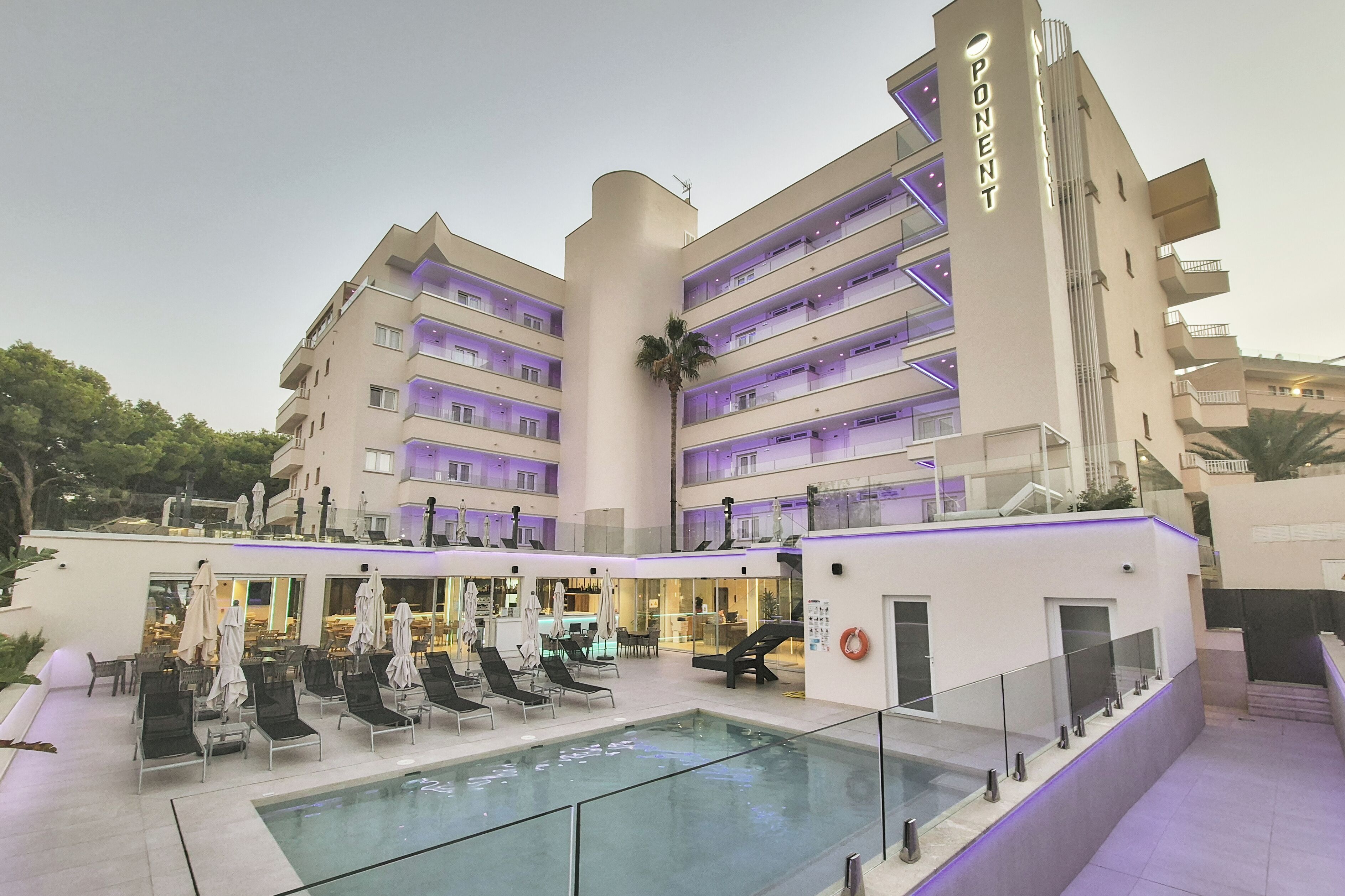 Un hotel con zona de piscina, varios balcones y un cartel que dice "PONENT".