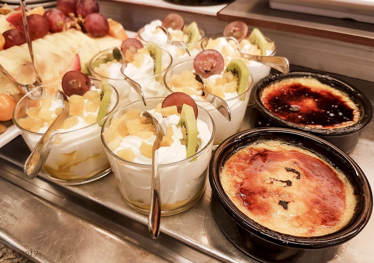 Una bandeja de postres con diversas opciones, entre ellas postres con fruta y una crème brûlée.