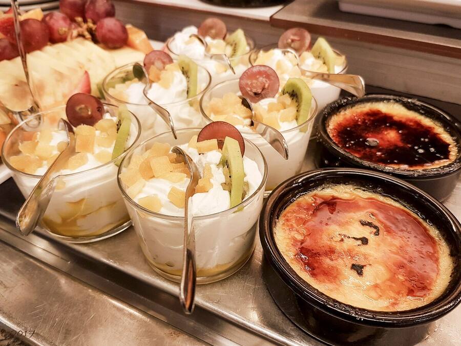 Una bandeja de postres con diversas opciones, entre ellas postres con fruta y una crème brûlée.