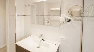 Un baño moderno con un lavamanos blanco, un espejo y un perchero para toallas.