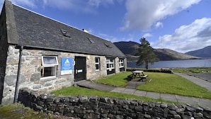A stone building with a sign indicating it is a hotel. - Ratagan Youth Hostel (Kyle)