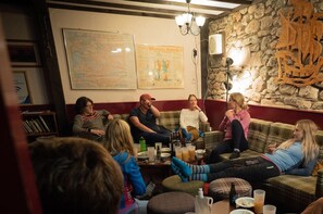 A group of people sitting on a couch in a room with a stone wall and a map on the wall. - Ratagan Youth Hostel (Kyle)