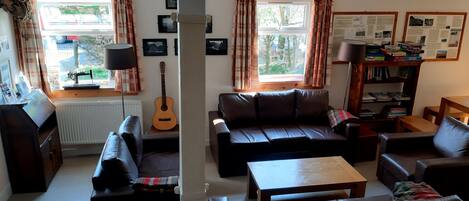 A living room with a sofa set, a coffee table, a guitar, and a bookshelf with informational posters.