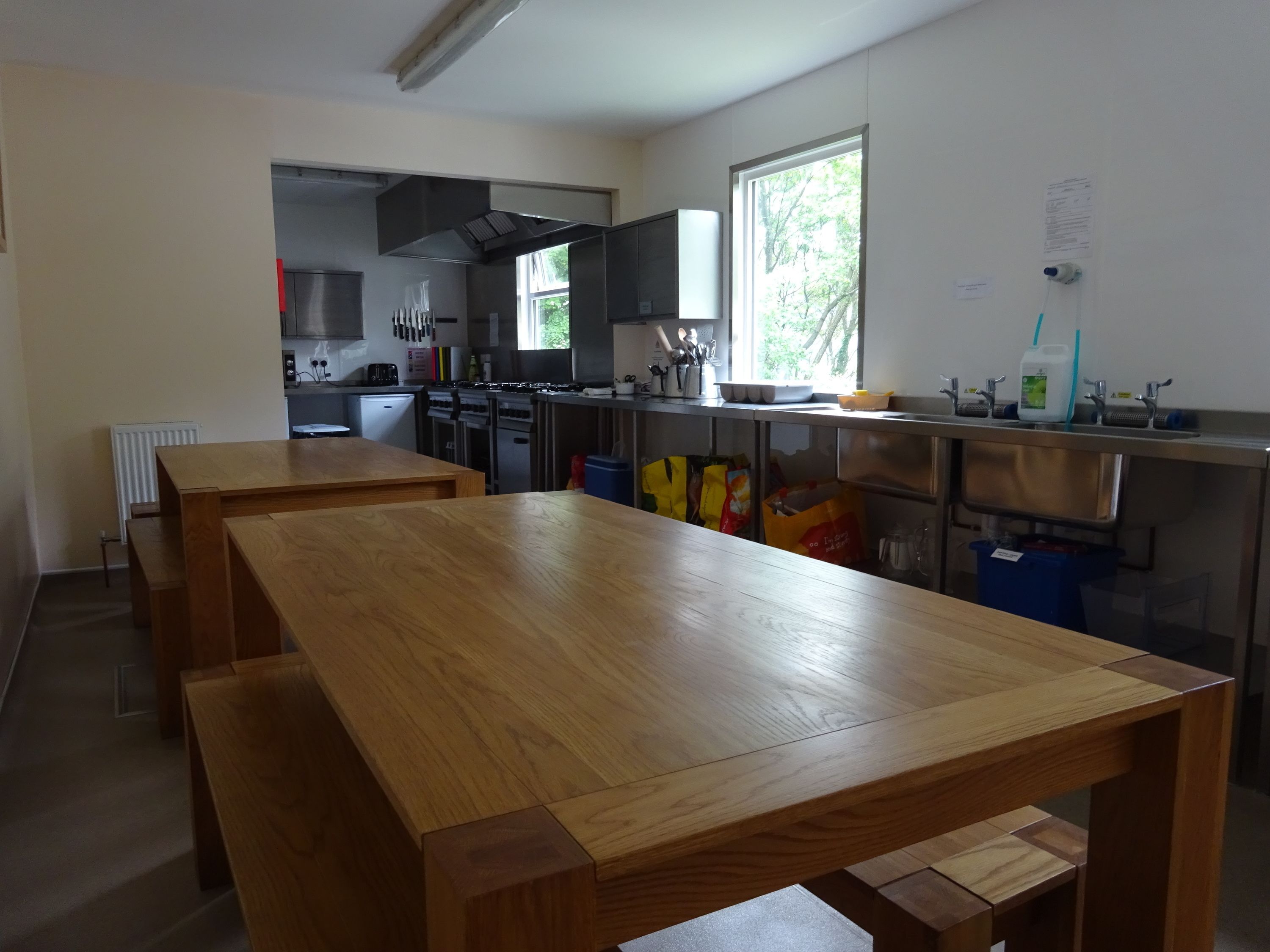 Una cocina moderna con mesas de madera, electrodomésticos de acero inoxidable y un ventanal que proporciona luz natural.
