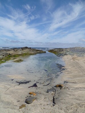 A coastal landscape with a clear water body, rocky formations, and a sandy beach. - Kirkwall Youth Hostel (Kirkwall)