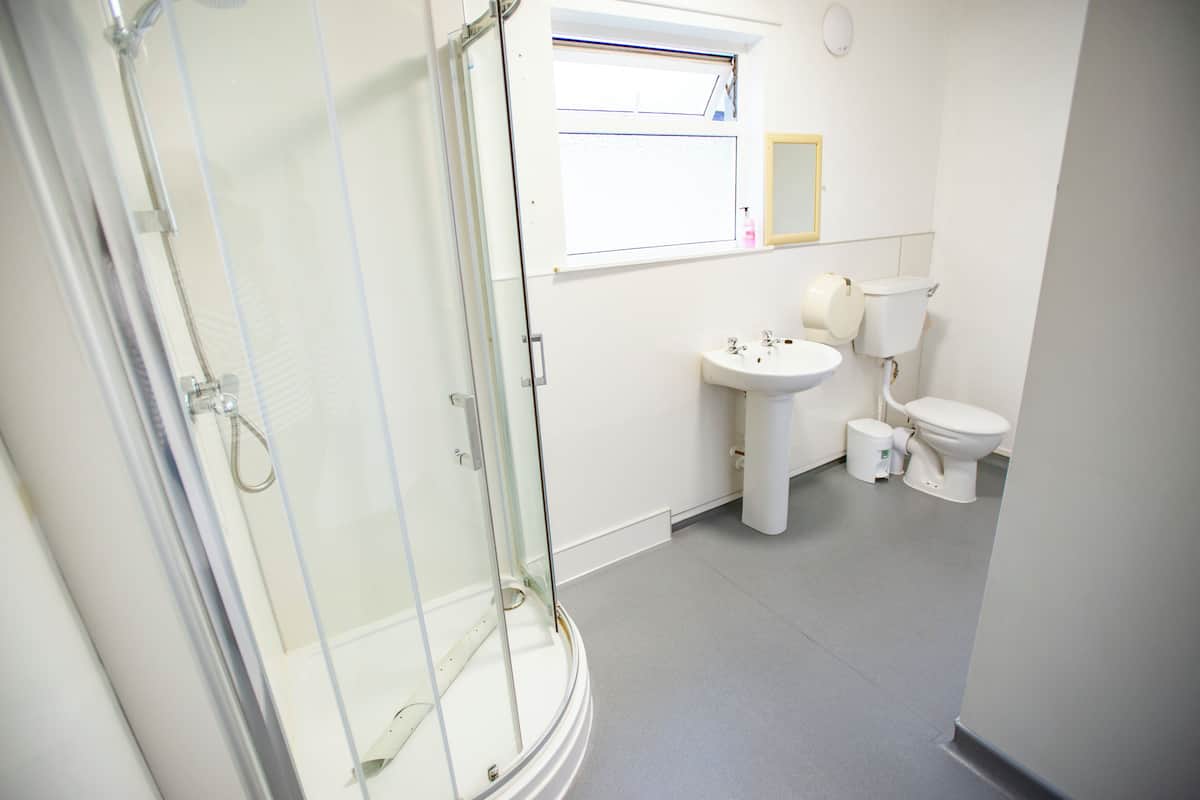 A bathroom with a glass shower enclosure, a sink, and a toilet.