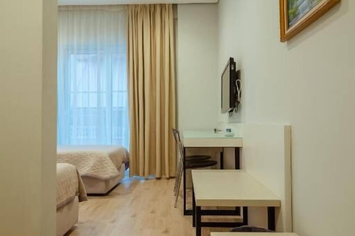Quarto compacto com uma cama, uma escrivaninha e uma cadeira.