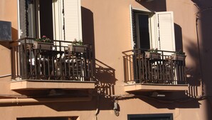 Un edifici amb dos balcons, cadascun amb una taula i cadires, i plantes en testos.