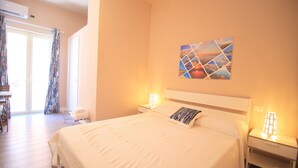 Habitació d'hotel ben a puntada amb un llit gran, una taula de nit amb una làmpada, un quadre penjat a la paret i una finestra amb cortines.