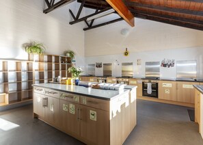 Une cuisine moderne dotée d’un îlot central, de meubles en bois, d’appareils électroménagers en acier inoxydable et d’un porte-couteaux suspendu.