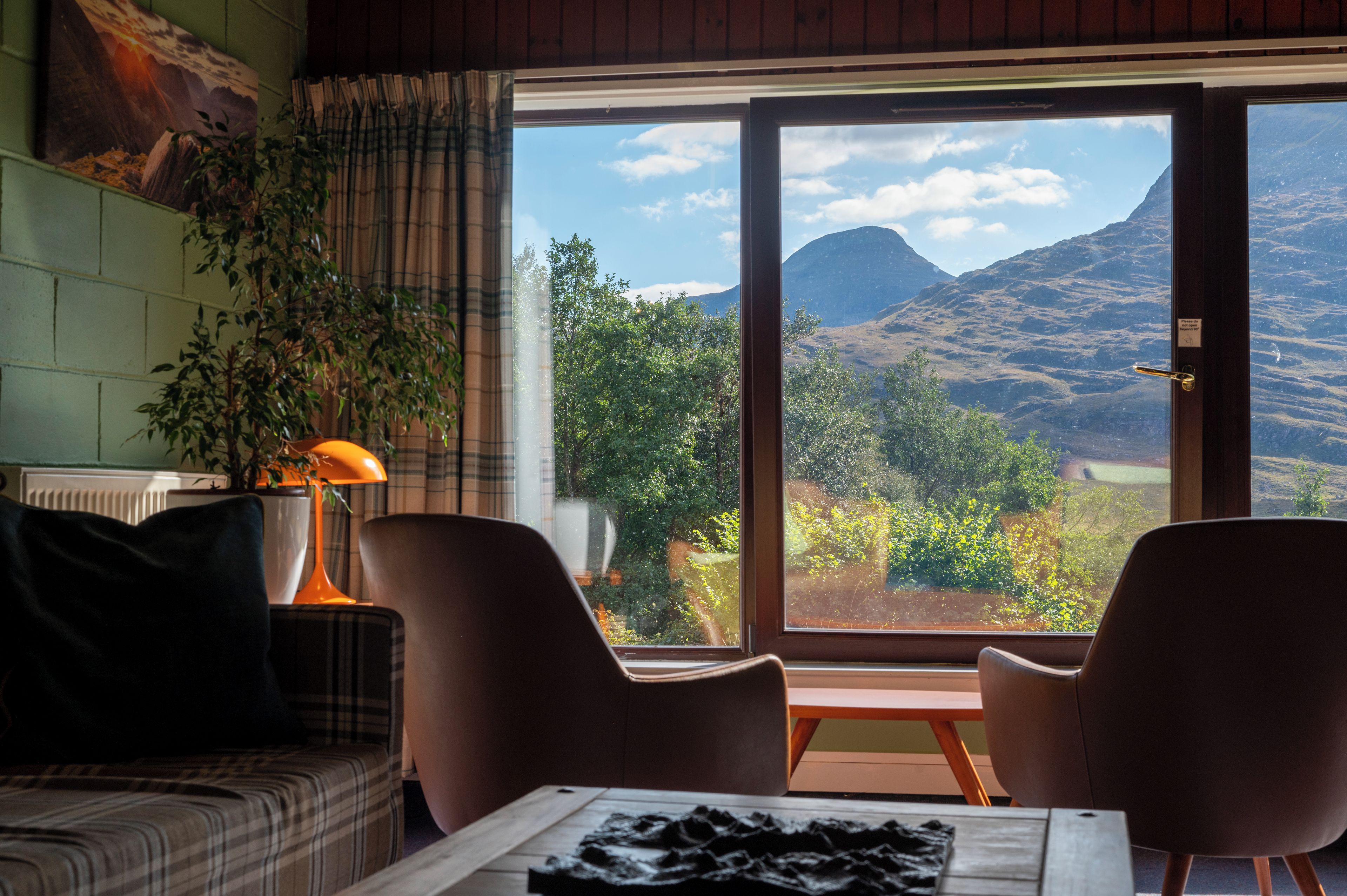 Une pièce avec vue sur les montagnes, comprenant un canapé, deux fauteuils, une table et une lampe.