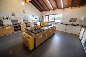 A kitchen with stainless steel appliances, a central island, and a window providing natural light. - Torridon Youth Hostel (Achnasheen)