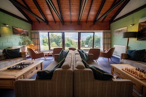 A cozy interior with a long couch, armchairs, a wooden coffee table, and a chessboard. - Torridon Youth Hostel (Achnasheen)