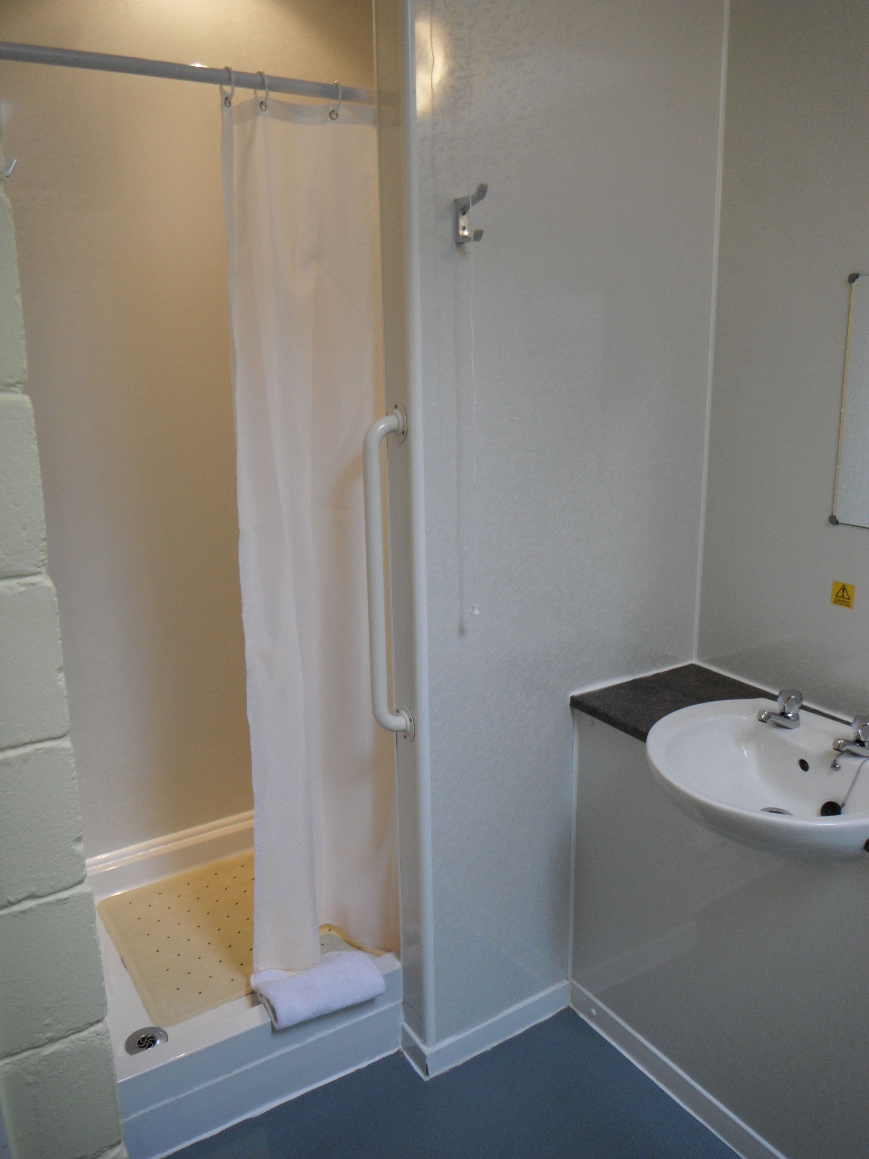 Un baño con ducha, lavabo y toallero.