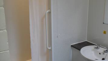 Un baño con ducha, lavabo y toallero.