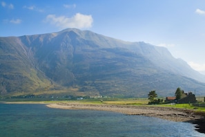 A coastal landscape with a mountain in the background, a small settlement, and a clear sky. - Torridon Youth Hostel (Achnasheen)