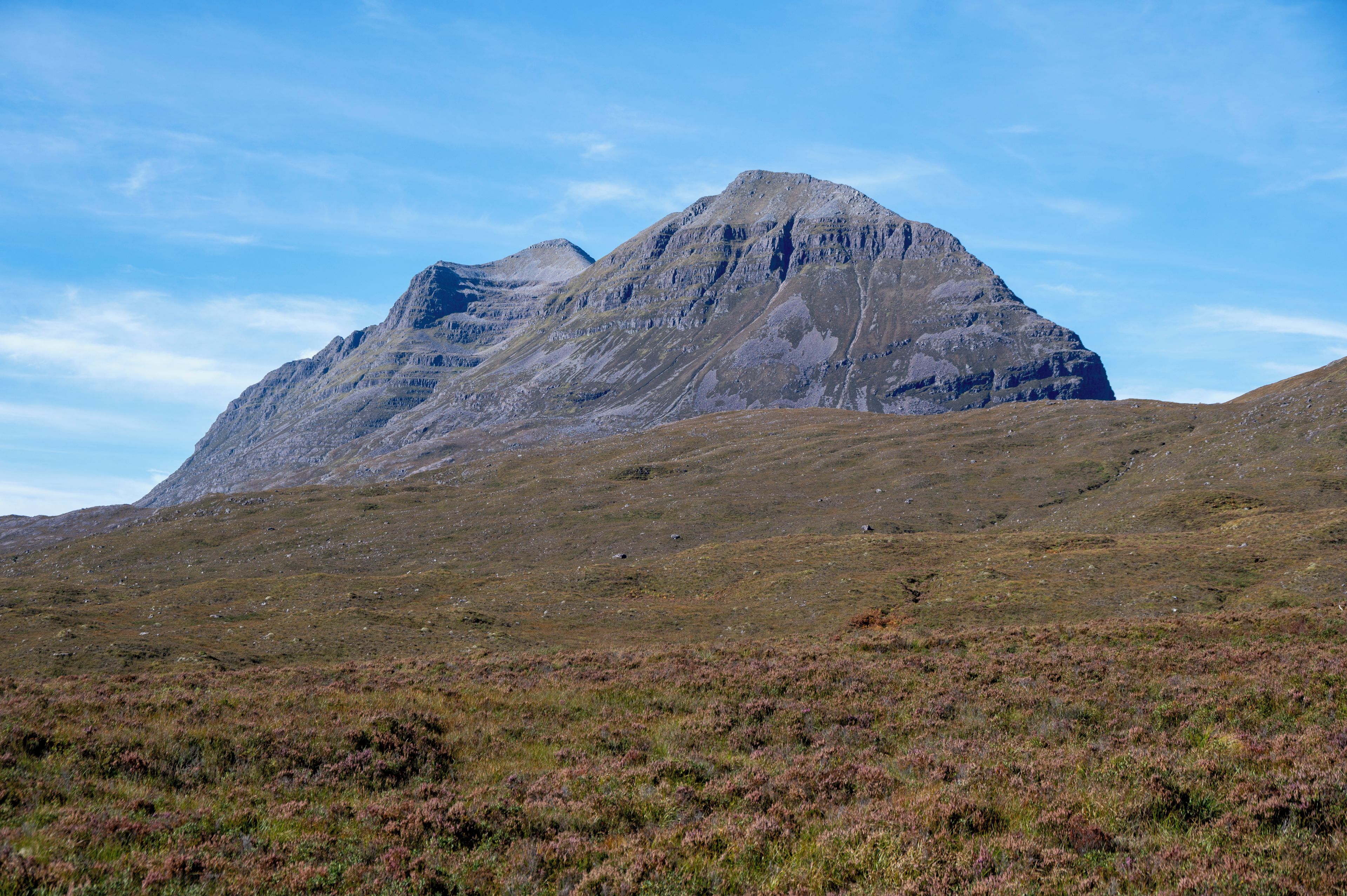 A mountain landscape with a prominent peak and a clear sky.