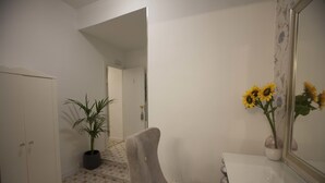 A hallway with a potted plant, a chair, a white door, and a mirror with a vase of sunflowers. - Hostal Boutique Palace - Adults Only (Madrid)