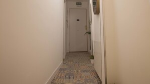 A narrow hallway with patterned floor tiles, a hanging light fixture, a door labeled "SALON," and a small potted plant. - Hostal Boutique Palace - Adults Only (Madrid)