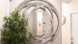 A circular mirror with a metallic frame, a door with a brass handle, and a potted plant. - Hostal Boutique Palace - Adults Only (Madrid)
