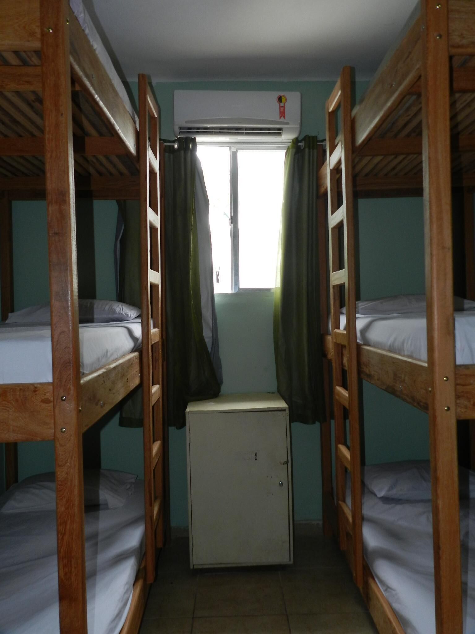 A room with bunk beds, a small white cabinet, and an air conditioning unit.