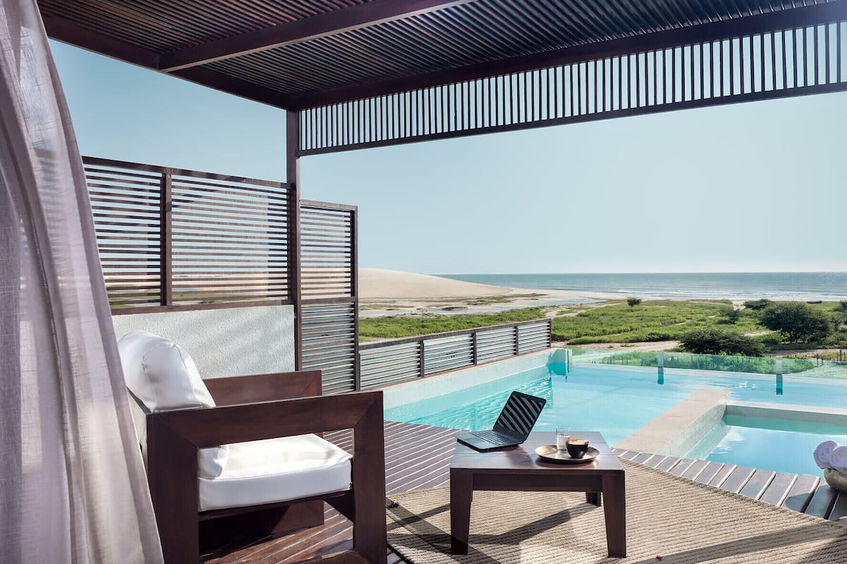 Un balcón con vista a la playa, una piscina y una silla.