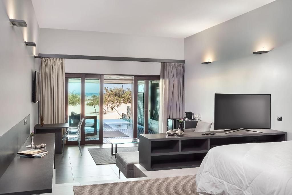 Habitación de hotel moderna con cama, televisor, escritorio y balcón con vistas.
