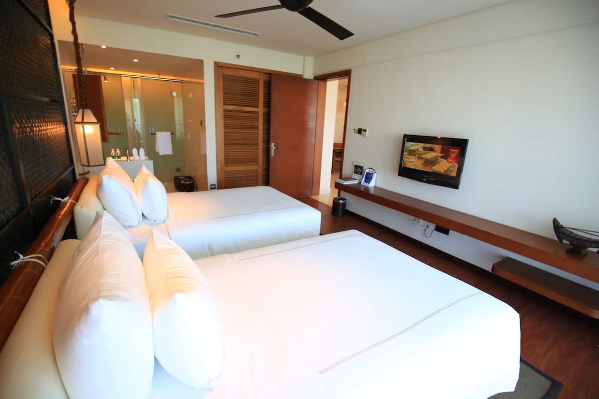 Una habitación de hotel con dos camas, televisión, escritorio y espejo.