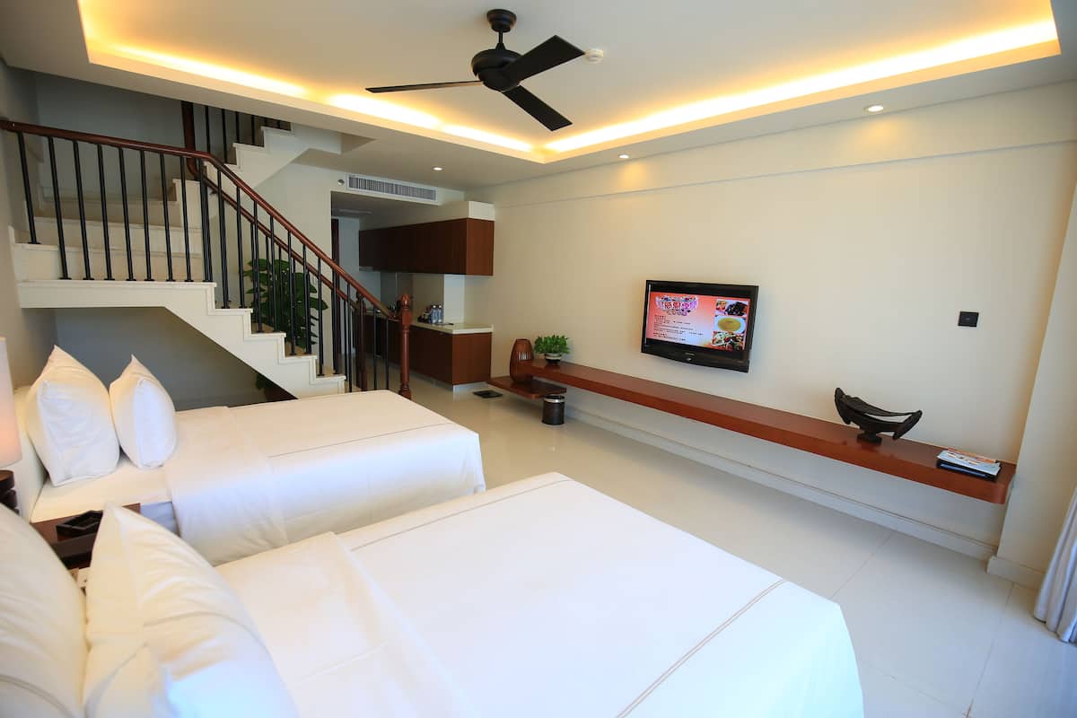 Una habitación de hotel moderna con una escalera, un televisor de pantalla plana, una mesa consola de madera y dos camas.